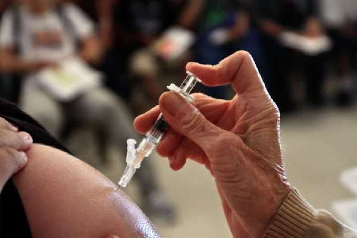 A student receives a vaccine against whooping cough at Huntington Park High School, 2011. Starting in 2014, parents will have to get a doctor to sign a form if they want to exempt their children from vaccination requirements.
