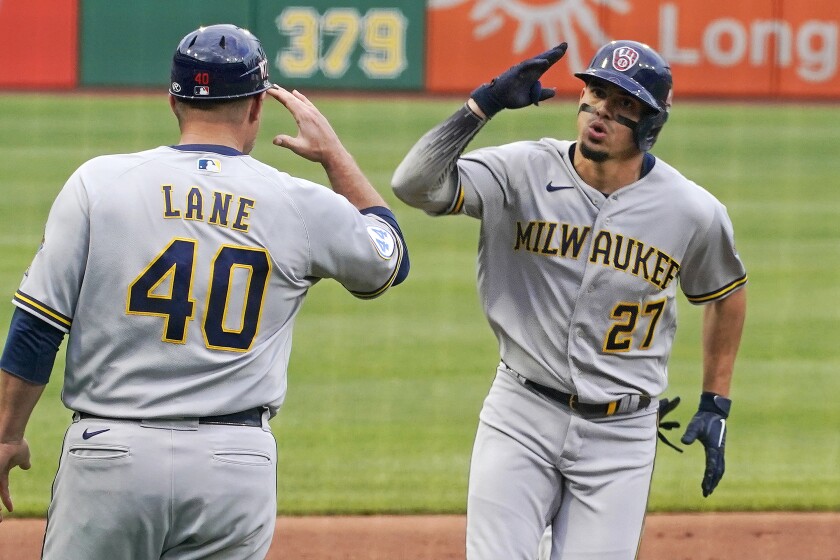 Milwaukee Brewers' Willy Adames (27) rounds third to greetings from coach Jason Lane (40) after hitting a solo home run off Pittsburgh Pirates starting pitcher JT Brubaker during the first inning of a baseball game in Pittsburgh, Friday, July 2, 2021. (AP Photo/Gene J. Puskar)