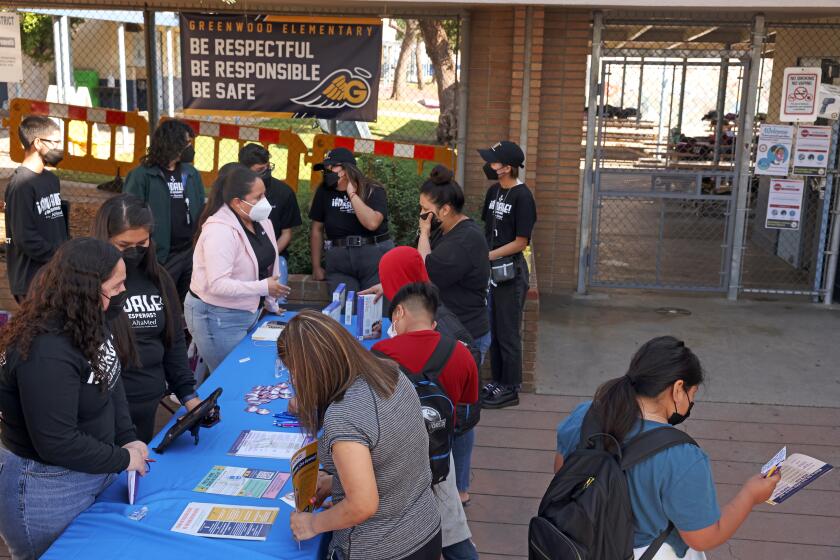MONTEBELLO, CA - MARCH 03: Workers with AltaMed Health Services table outside Greenwood Elementary School to share information about the COVID-19 vaccination and distribute test kits on Thursday, March 3, 2022 in Montebello, CA. (Dania Maxwell / Los Angeles Times)