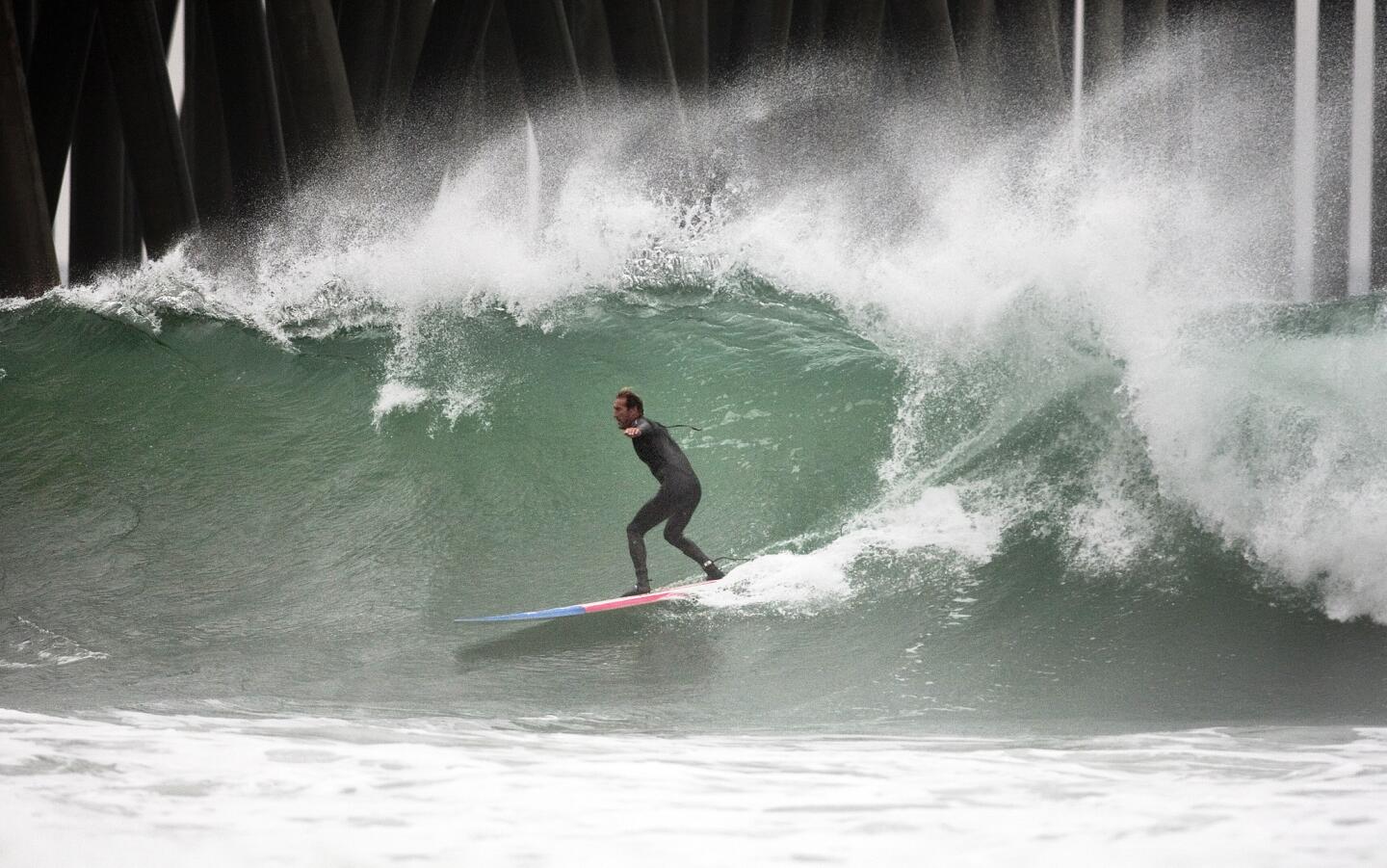 Amid light rain, Mike Watson of Huntington Beach rides a big wave in Huntington.