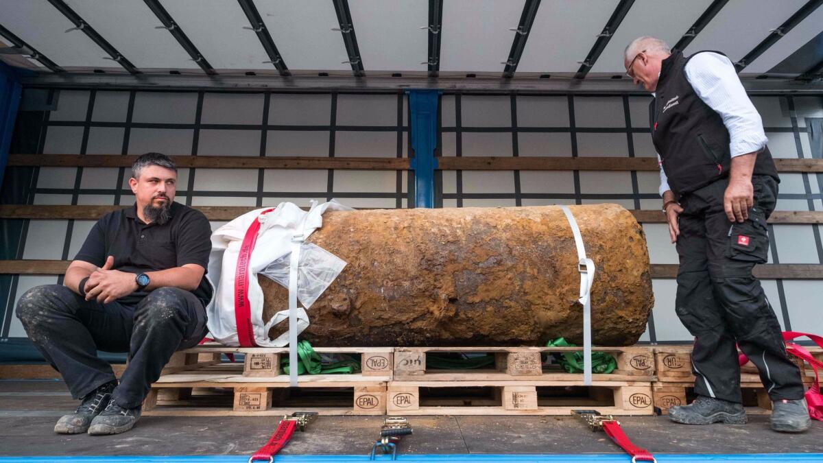 Bomb disposal experts Dieter Schwetzler, right, and Rene Bennert pose with a World War II-era bomb they defused in Frankfurt, Germany.