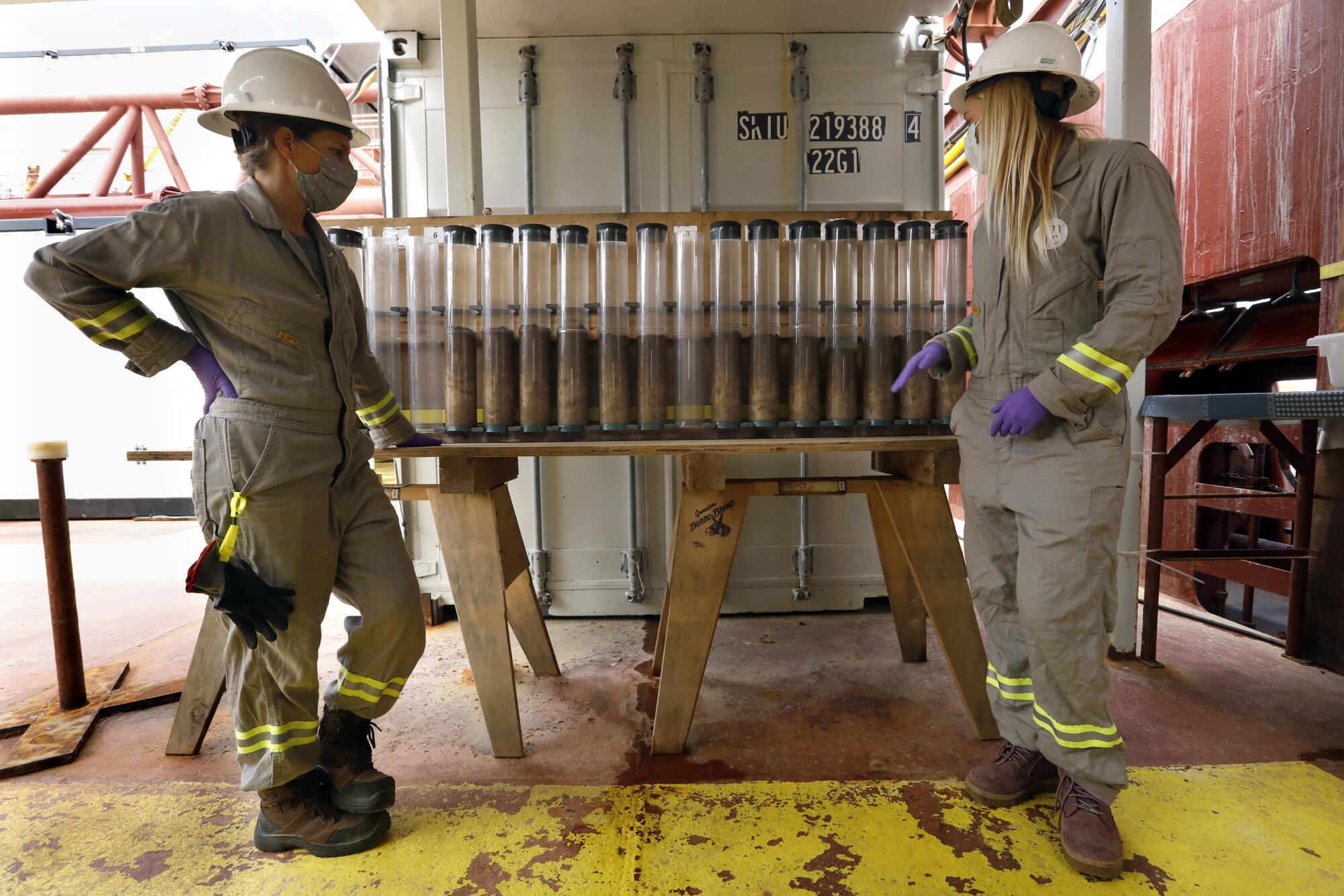 Two scientists aboard a research vessel look at samples retrieved from the seafloor