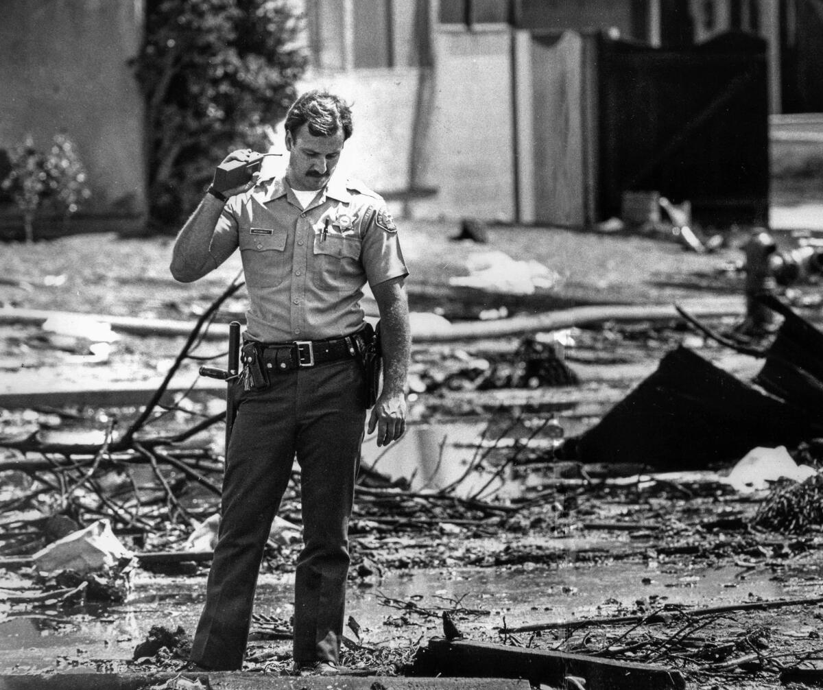 Aug. 31, 1986: A deputy stands amid debris on Holmes Avenue after the jetliner crash in Cerritos. 