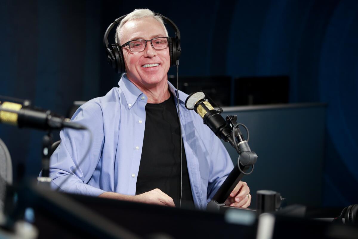 Dr. Drew Pinsky sits behind a microphone in a radio studio