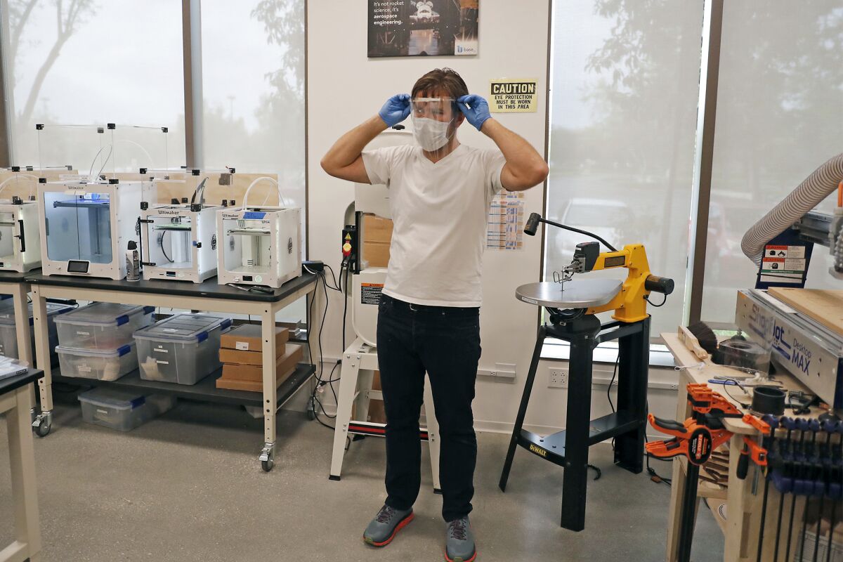 Jesse Jackson, an associate professor of art at the Claire Trevor School of the Arts, demonstrates a face shield during a tour at the UCI Beall Applied Innovation Cove in Irvine on Tuesday.