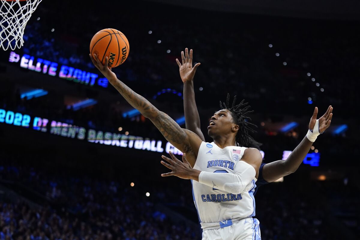 North Carolina's Caleb Love goes up for a shot past St. Peter's Clarence Rupert during the first half of a college basketball game in the Elite 8 round of the NCAA tournament, Sunday, March 27, 2022, in Philadelphia. (AP Photo/Chris Szagola)