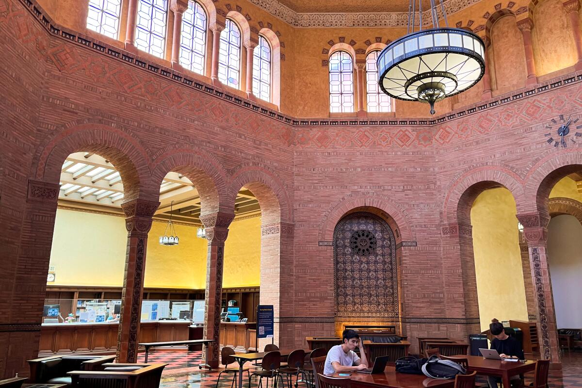 Powell Library rotunda features arched windows and a glass-and-metal hanging light fixture.