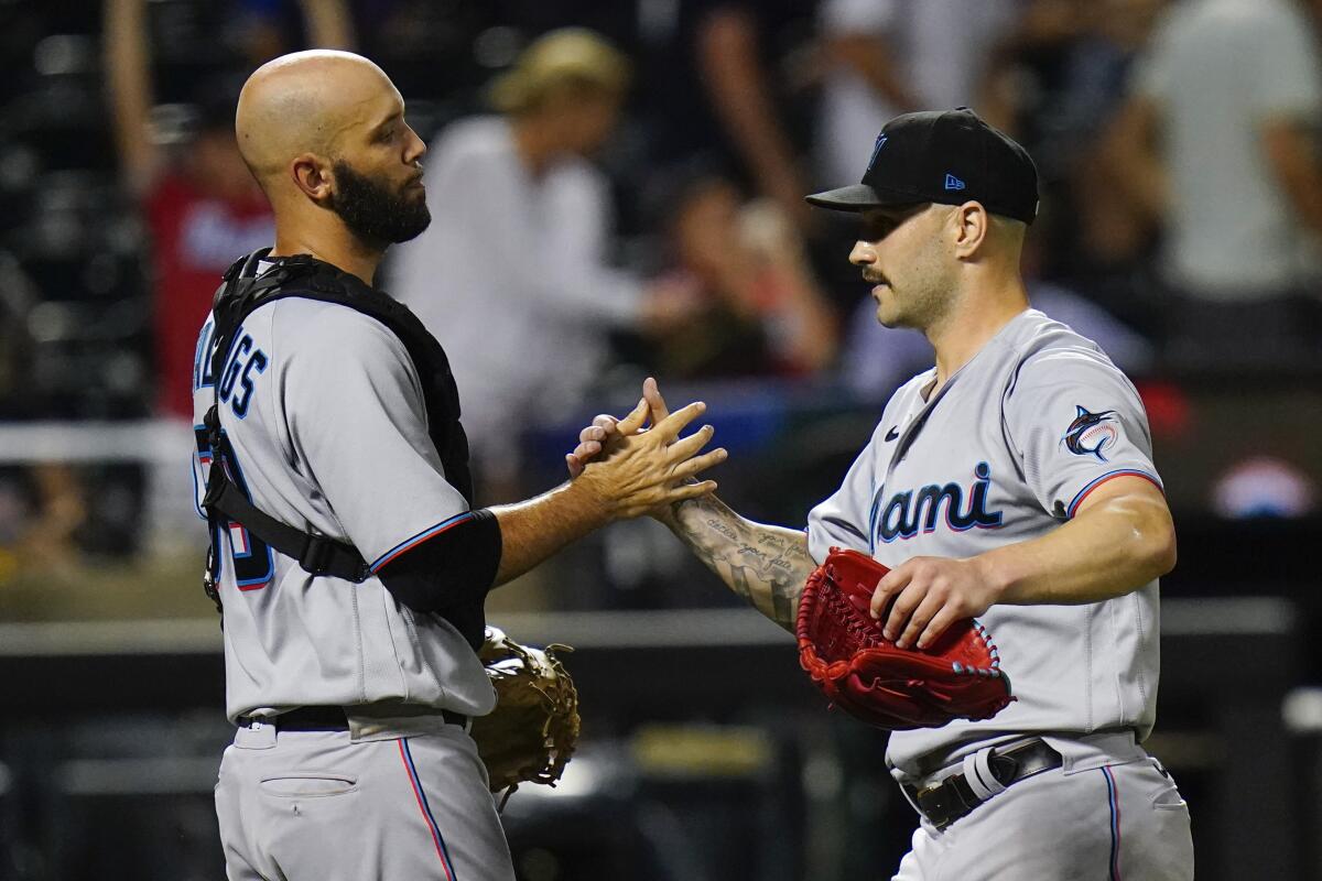 Miami Marlins manager Don Mattingly, left, and a trainer, right