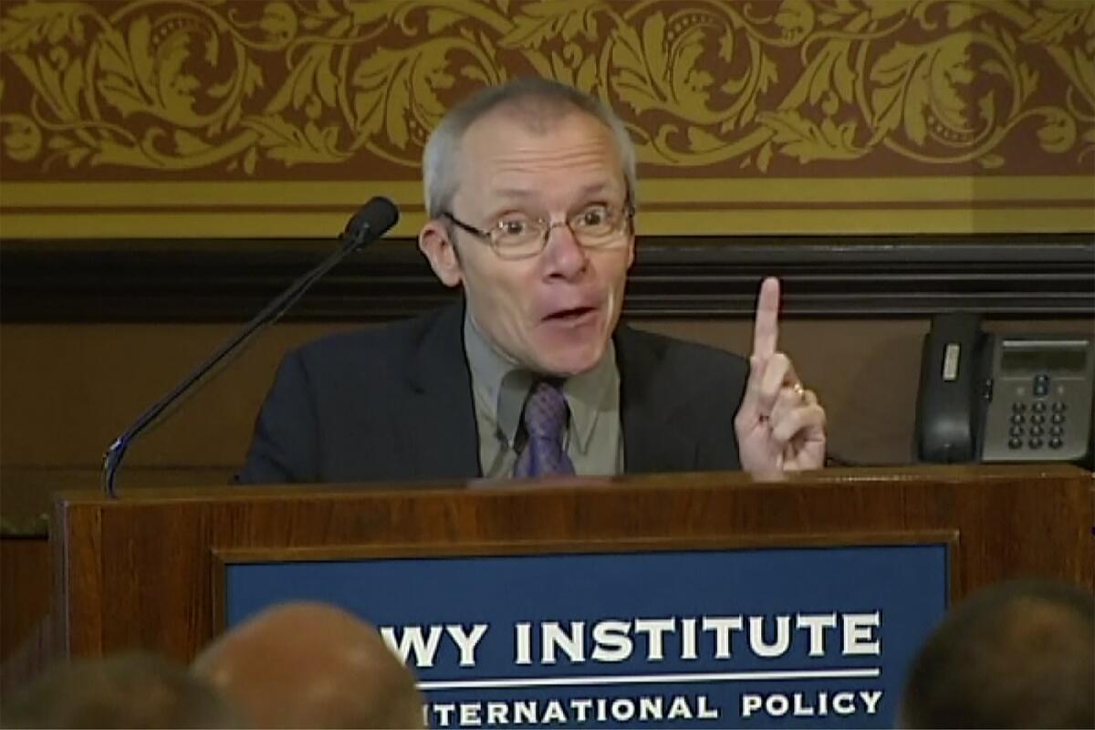 Man pointing his finger upward as he speaks at an event