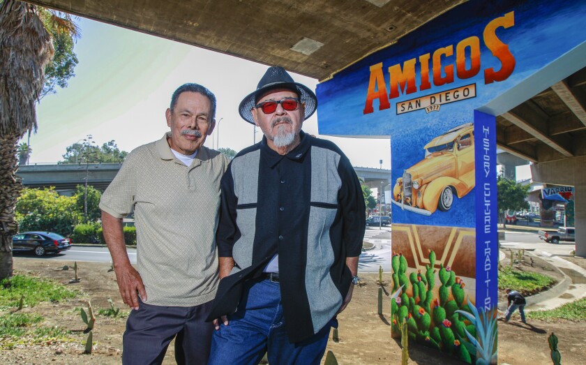 Rigoberto Reyes (right) and artist Salvador Barajas pose for photos in Chicano Park with a new mural on Nov. 7, 2019 in San Diego. Barajas painted the mural. Reyes is on of the notables whose face appears on the work.