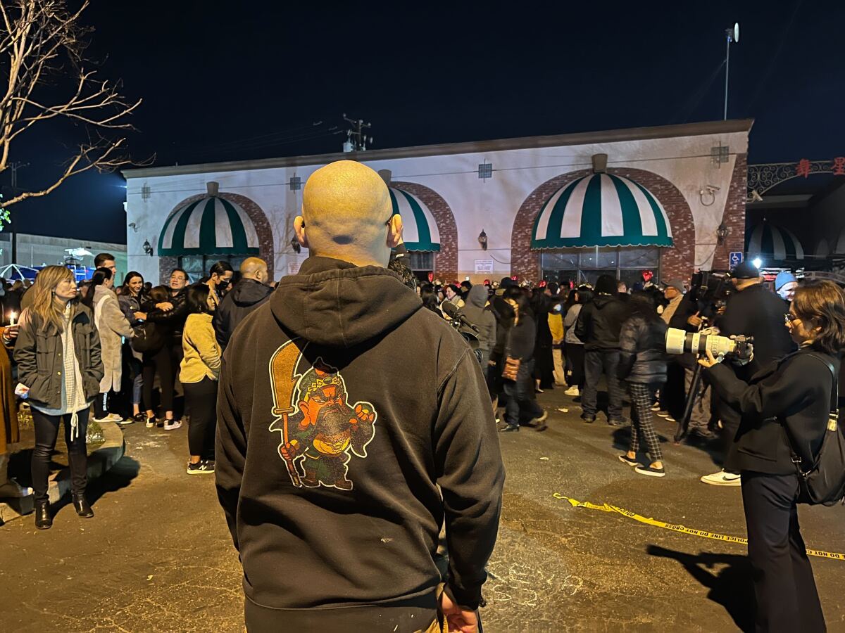 Jonathan D. Chang stands facing the vigil at Star Dance Studio in Monterey Park on Jan. 25, 2023.