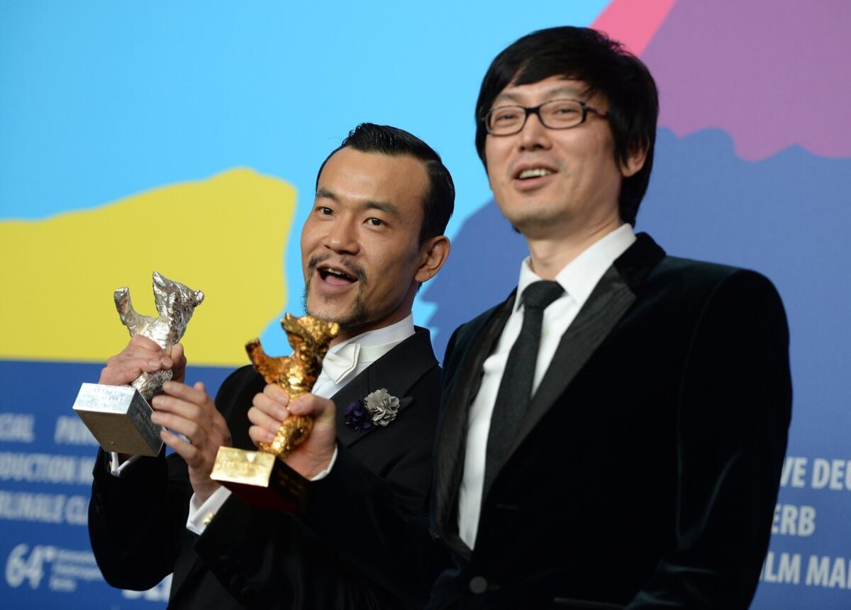 "Black Coal, Thin Ice" star Fan Liao, left, holds the Silver Bear for best actor, and director Yinan Diao has the Golden Bear award for best film at the Berlin Film Festival.
