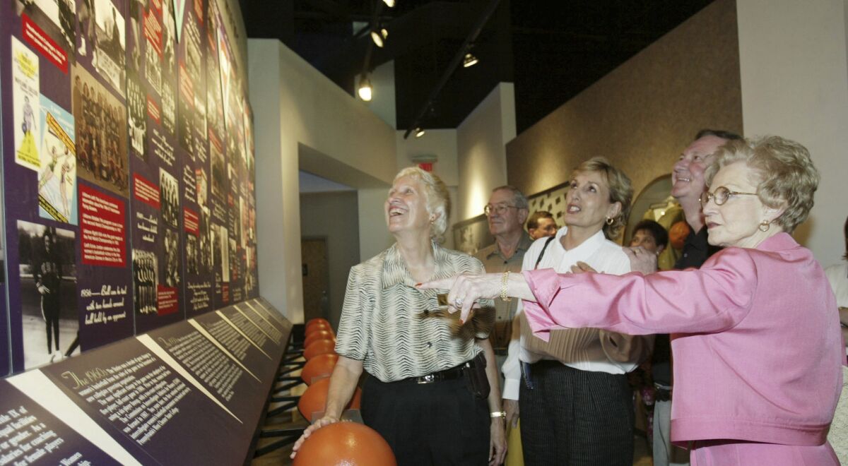 Wilda Redin, right, widow of Claude Hutcherson, checks the display for the "First 100 Years" of women's basketball.