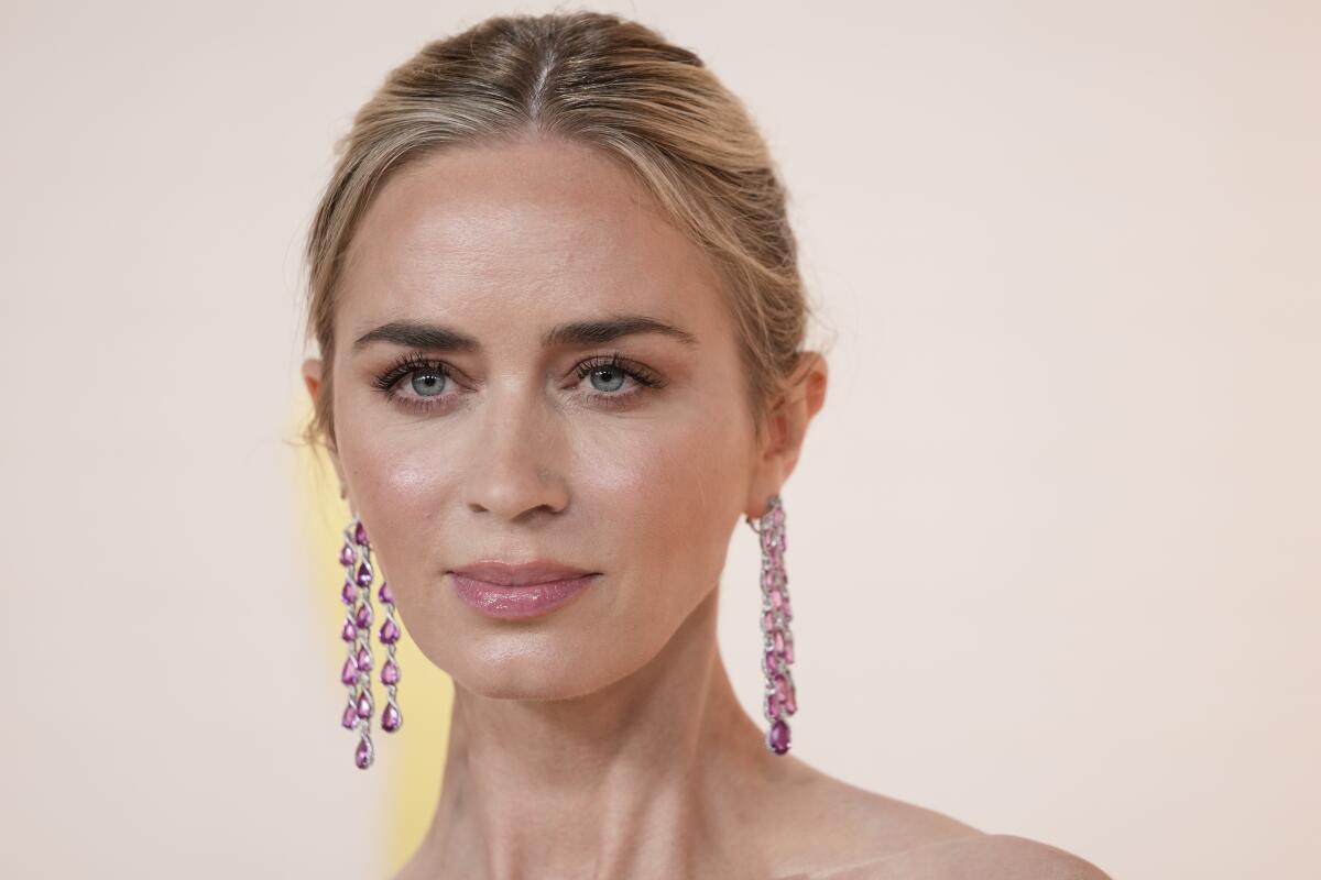 Emily Blunt looks straight ahead in dangling pink earrings with her hair pinned up