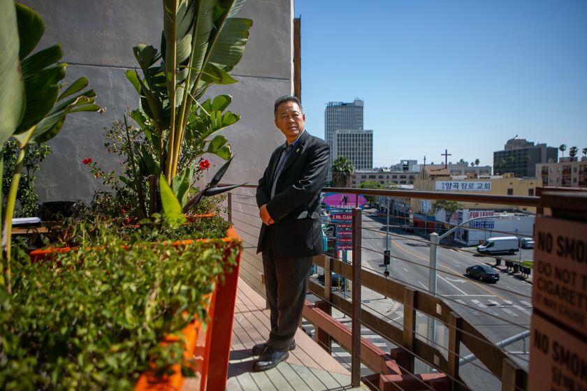 LOS ANGELES, CA - APRIL 26: Standing on the roof of California Marketplace in the same spot where he photographed Korean Americans holding guns defending the grocery store during the riots, T.C. Kim, a longtime community leader (and a former journalist who had taken photos for Korean newspapers during the unrest) poses for a portrait on Tuesday, April 26, 2022 in Los Angeles, CA. (Jason Armond / Los Angeles Times)