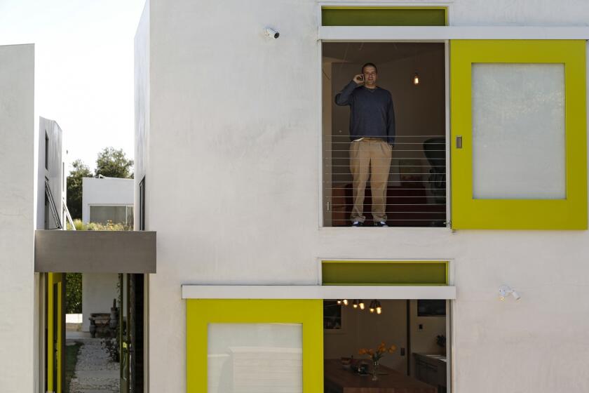 Jamie Sobieski stands at a second-floor doorway whose sliding track creates an arresting design as seen from the second floor of another building on the property.