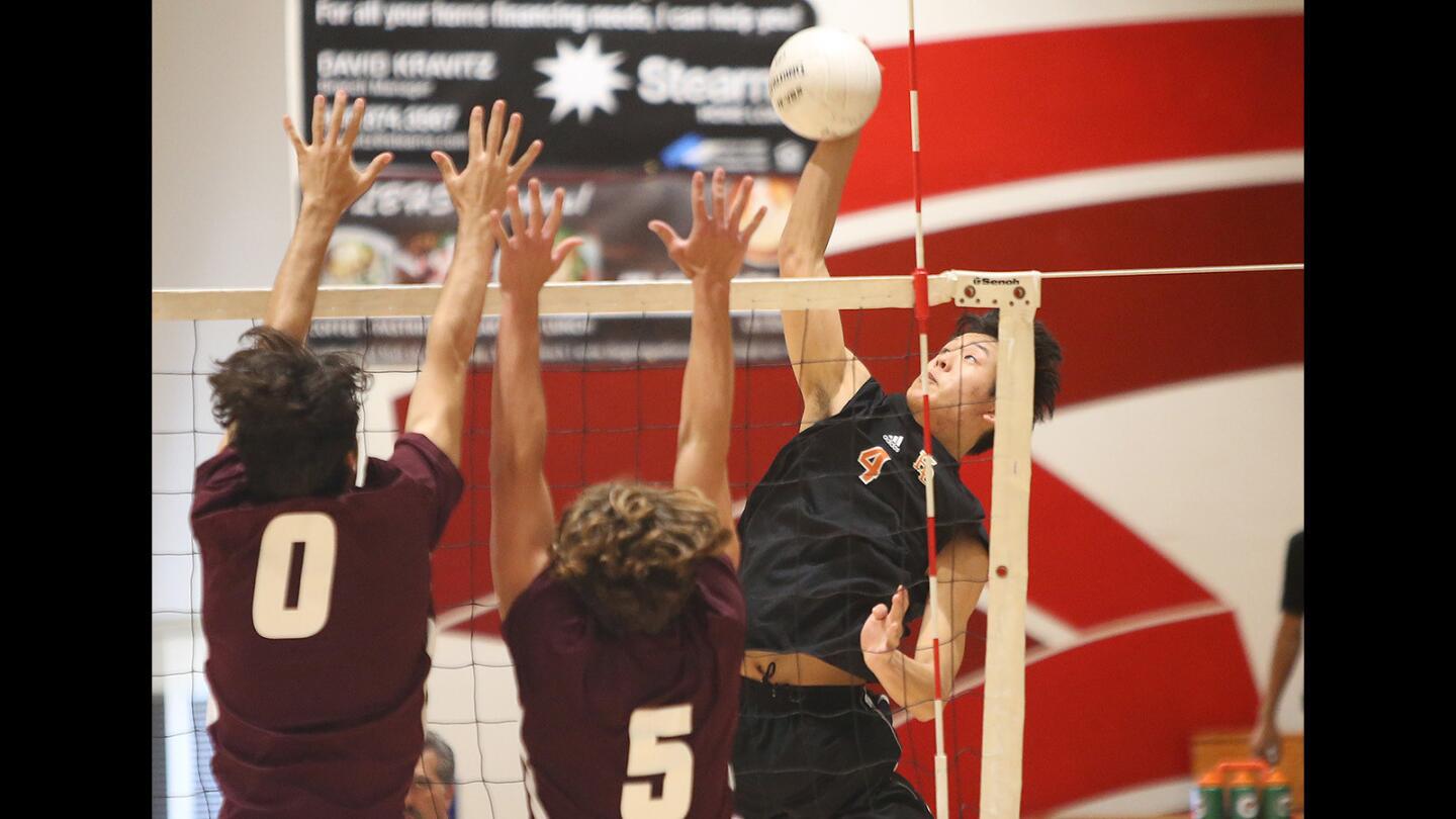 Huntington Beach High's Sinjin Choi puts the ball away past Laguna Beach High blockers Milo Zegawitz (0) and Ayrton Garcia (5) during the first round of the CIF Southern Section Division 1 playoffs at Laguna Beach on Tuesday.