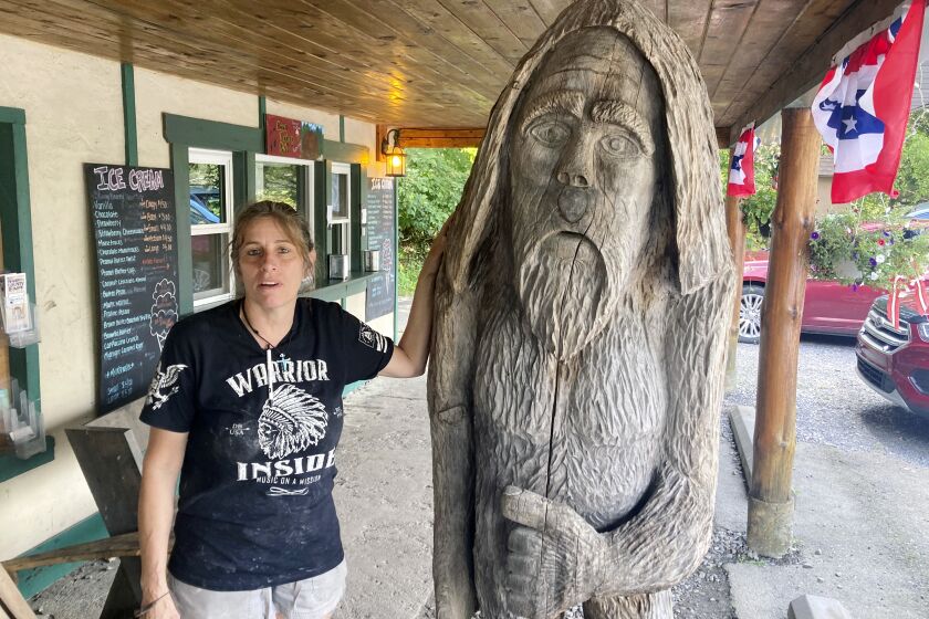 FILE - Pauline Bauer leans against a wooden statue outside Bob's Trading Post, her restaurant in Hamilton, Pa., July 21, 2021. Bauer, who screamed death threats directed at then-House Speaker Nancy Pelosi while storming the U.S. Capitol on Jan. 6, 2021, was sentenced on Tuesday to two years and three months in prison. (AP Photo/Michael Kunzelman)