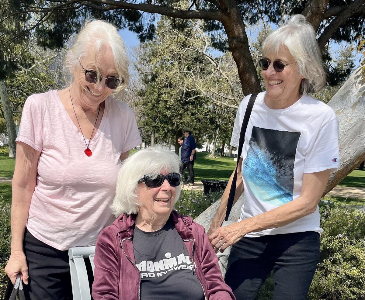 Three gray-haired women share a laugh in a Beverly Hills park.