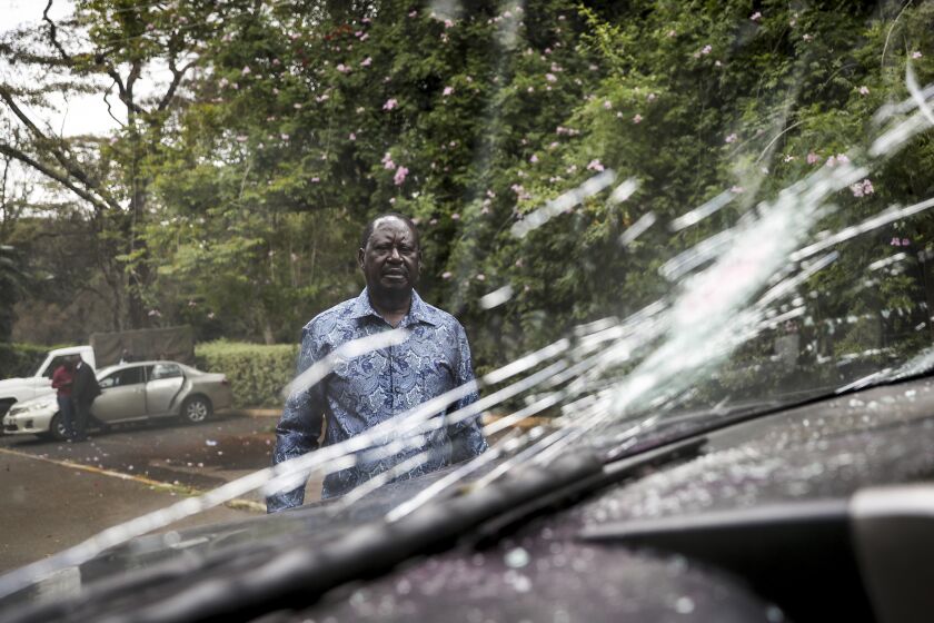 Kenya's opposition leader Raila Odinga stands next to one of his vehicles he says was struck by a teargas canister fired by riot police, at his home in Nairobi, Kenya Friday, March 31, 2023. In an interview with The Associated Press on Friday, Odinga denounced the point-blank firing of a tear gas canister at local journalists during his latest anti-government protest as a "primitive act of intolerance" and vowed to go to court over what he called an attempt on his own life. (AP Photo/Brian Inganga)