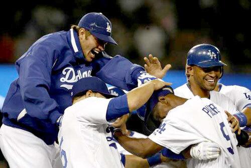 Dodgers left fielder Juan Pierre (at right with head bowed) is swarmed by teammates after drawing a bases-loaded walk by Angels reliever Jose Arredondo in the 10th inning that drove in the winning run Saturday night.