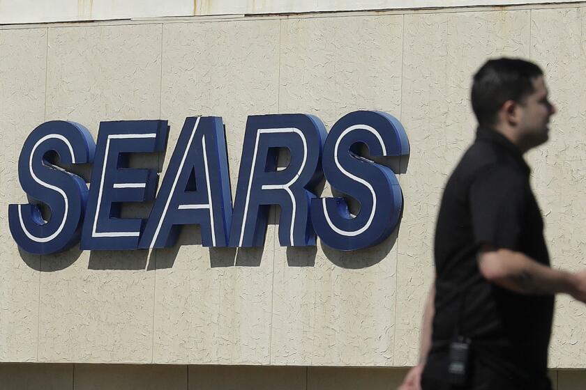 FILE- In this March 28, 2018, file photo, a man walks in front of a Sears sign in San Bruno, Calif. Sears is adding a restructuring expert to its board, suggesting that the company may be preparing to take drastic actions to survive or to protect its remaining assets. The Hoffman Estates, Ill., company, which also owns Kmart, said Tuesday, Oct. 9, it was bringing on board Alan Carr, managing member and CEO of Drivetrain LLC, a restructuring advisory firm. (AP Photo/Jeff Chiu, File)