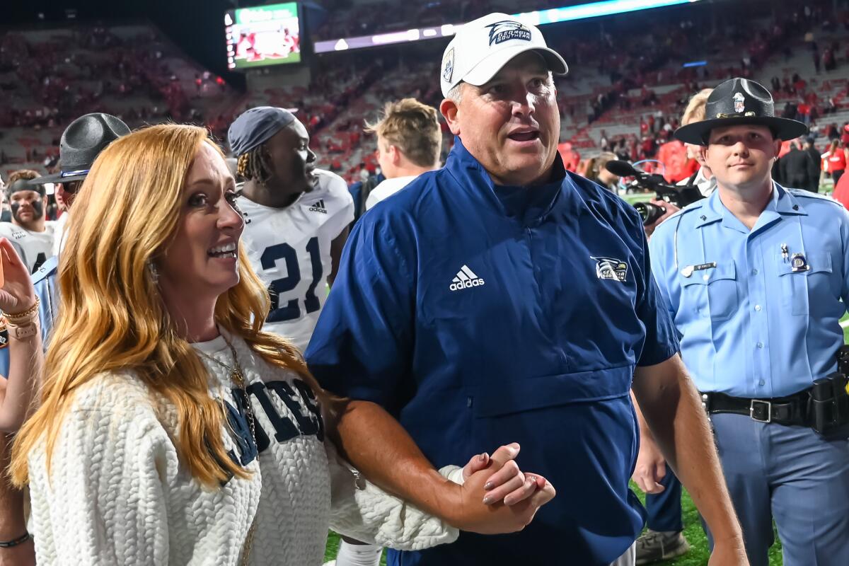 Georgia Southern coach Clay Helton and his wife, Angela, leave the field after the Eagles' upset over Nebraska.