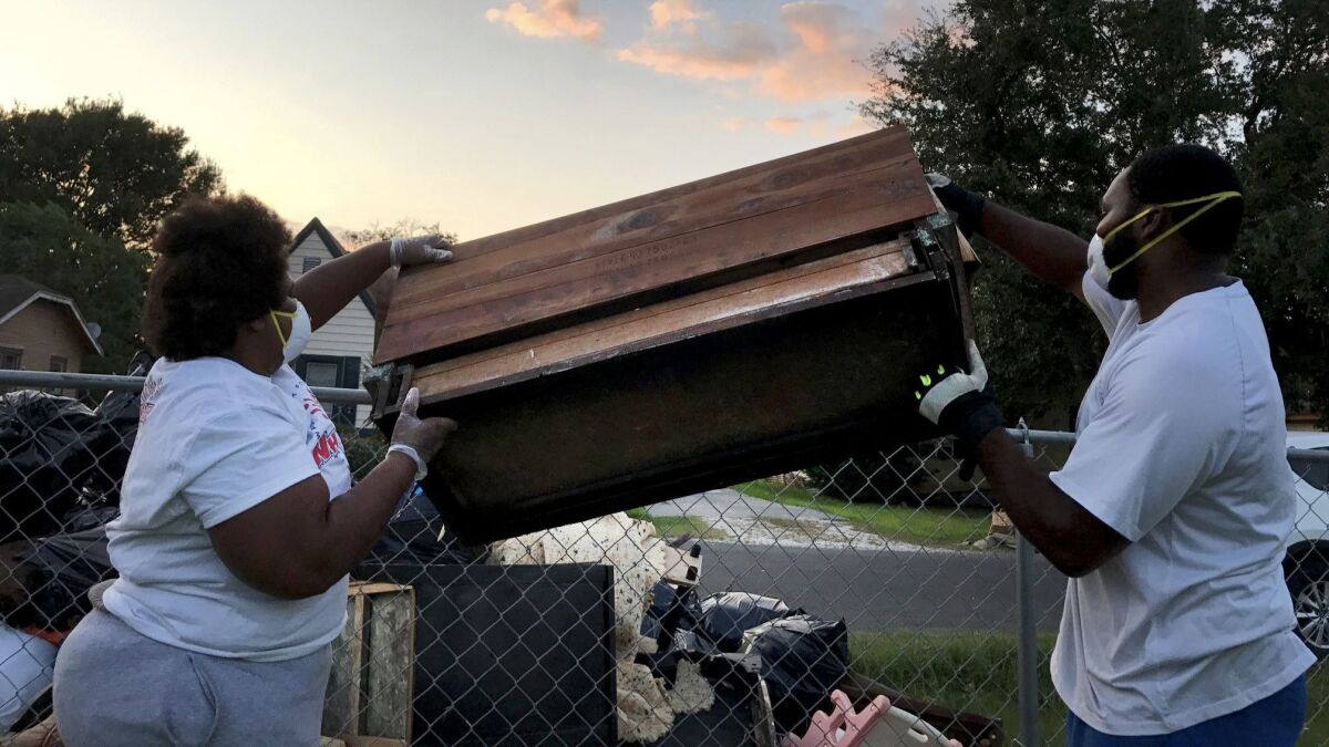 Maxine Williams and Steven Williams toss out a waterlogged hope chest damaged beyond repair in Port Arthur. The city was flooded after Hurricane Harvey struck the Gulf Coast.