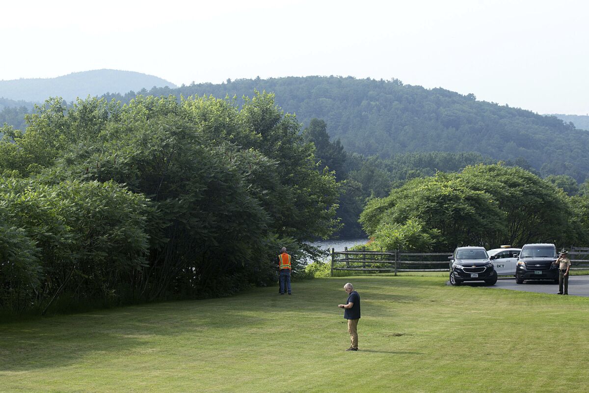 Investigators, including those from the Federal Aviation Administration, gather along the Connecticut River and Route 25 in Bradford, Vt., on Friday, July 16, 2021, following the death of a hot-air ballonist. Brian Boland, 72, the pilot of the hot-air balloon that had been carrying a total of five people, died Thursday, July 15, 2021, after becoming entangled in gear underneath the basket and then falling to the ground in Bradford, Vermont State Police said. Some after take off, the balloon touched down in a field and one passenger fell out, but was unhurt. After the pilot’s death, three other passengers remained in the balloon until it caught in a grove of trees about 1.5 miles (2.4 kilometers) farther north in Piermont, New Hampshire, where they escaped without injury. (Geoff Hansen/The Valley News via AP)