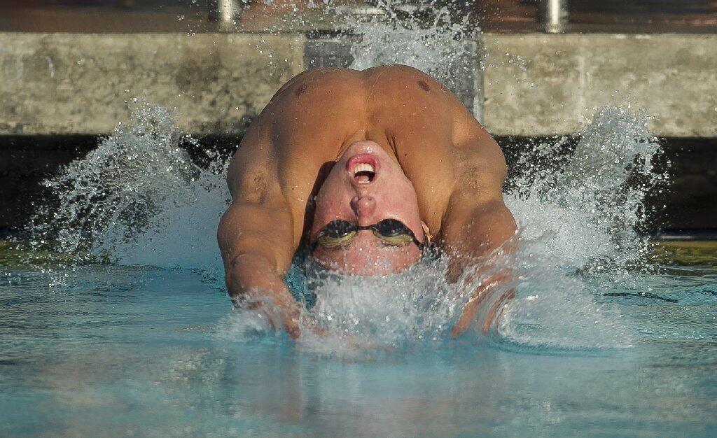 Corona del Mar's Tanner Pulice starts off the blocks during the 100 yard backstroke during a Pacific Coast League meet against Irvine at Woollett Aquatic Center on Wednesday.