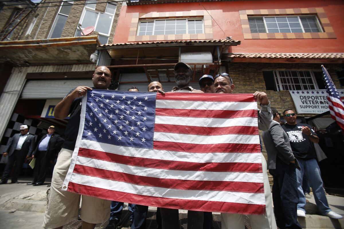 Deported vets holding a U.S. flag outside the Deported Veterans office.