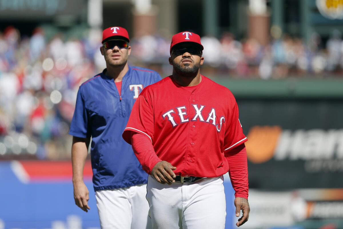 Rangers' Prince Fielder and Colby Lewis, rear, walk off the field after not playing against the Mariners on June 5.