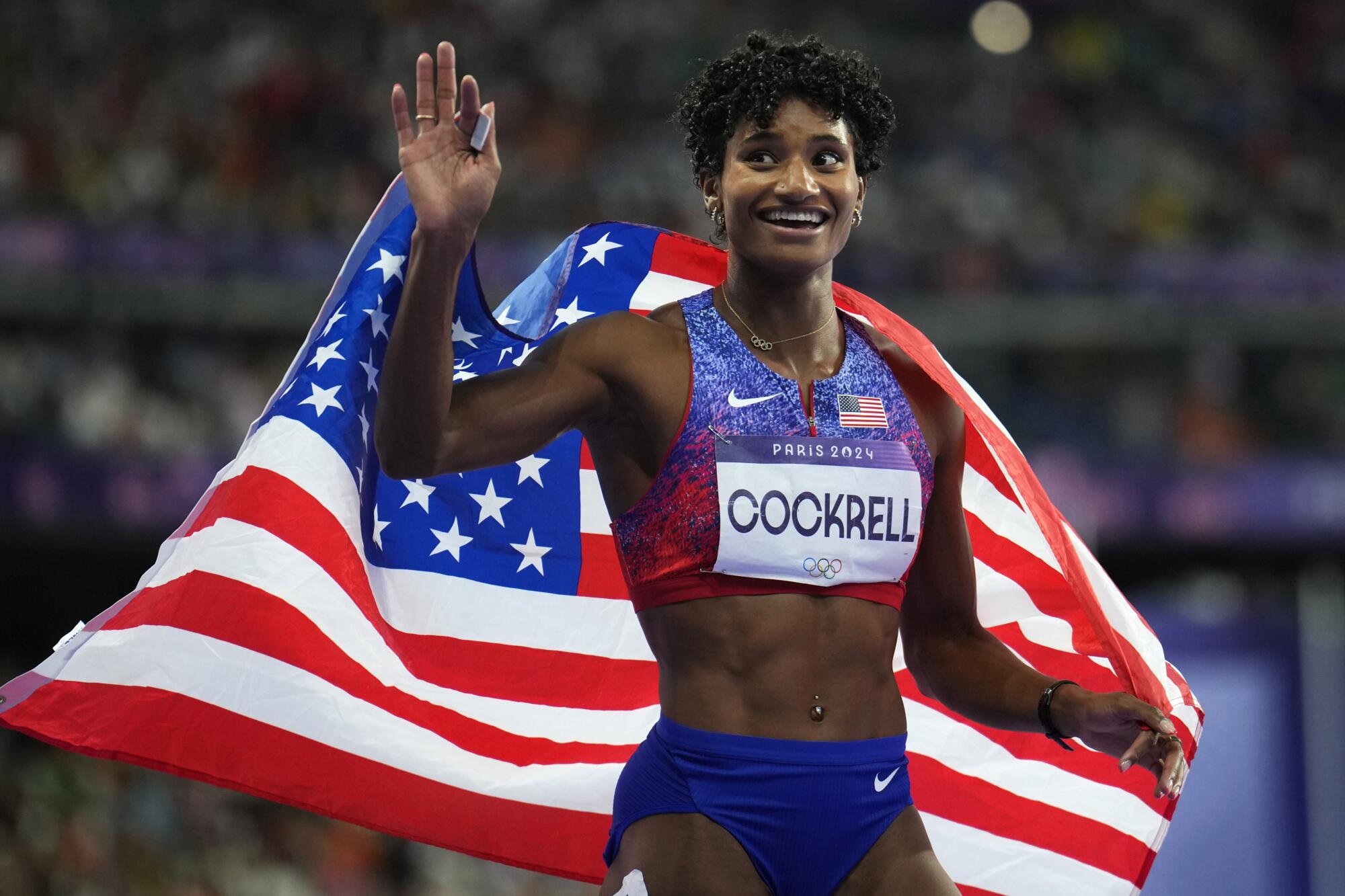 U.S. athlete Anna Cockrell waves while draped in a U.S. flag s after winning the silver medal in the 400-meter hurdles