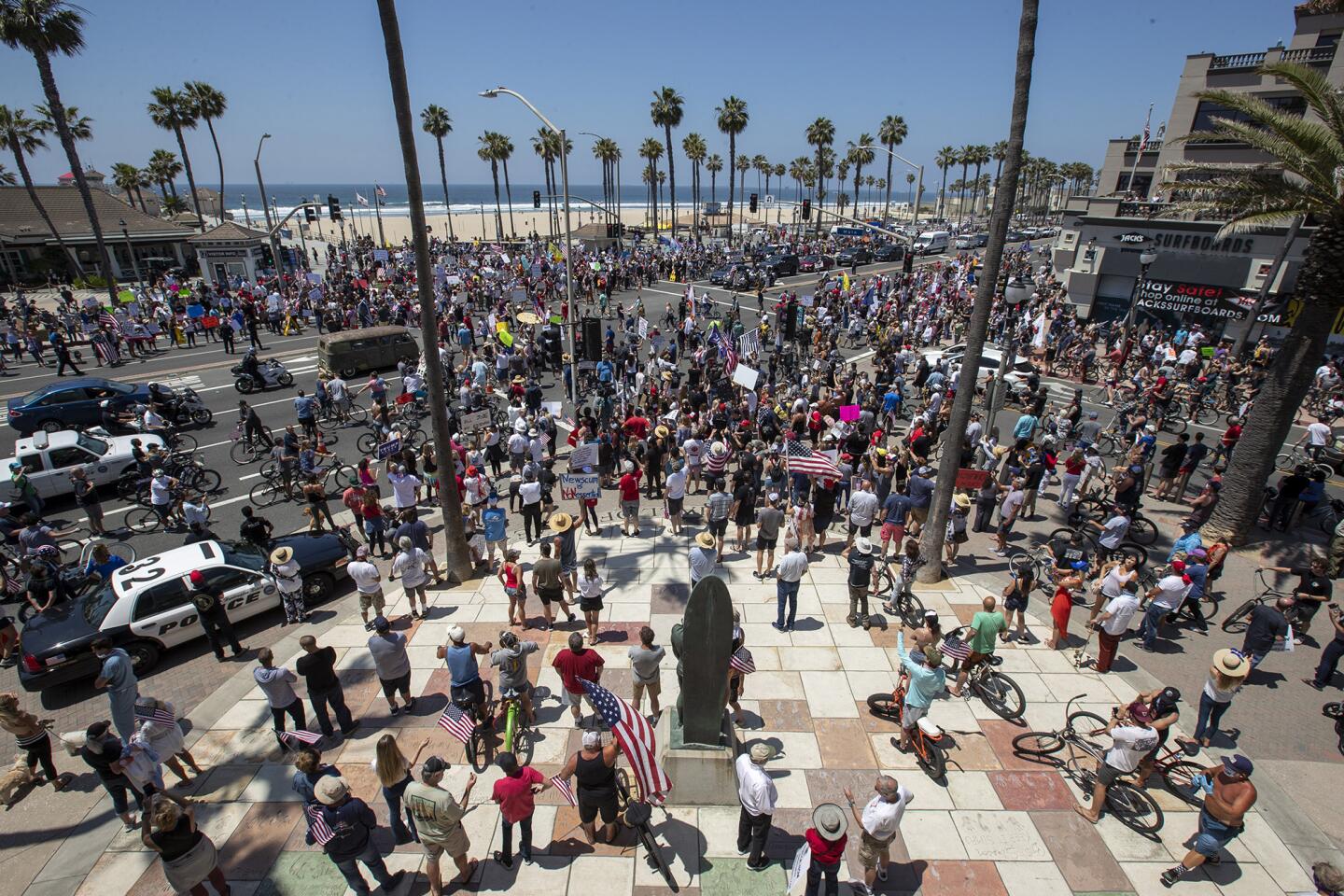 A large crowd gathers during a protest of the governor's stay-at-home orders on Main Street and Pacific Coast Highway in Huntington Beach on Friday, May 1.