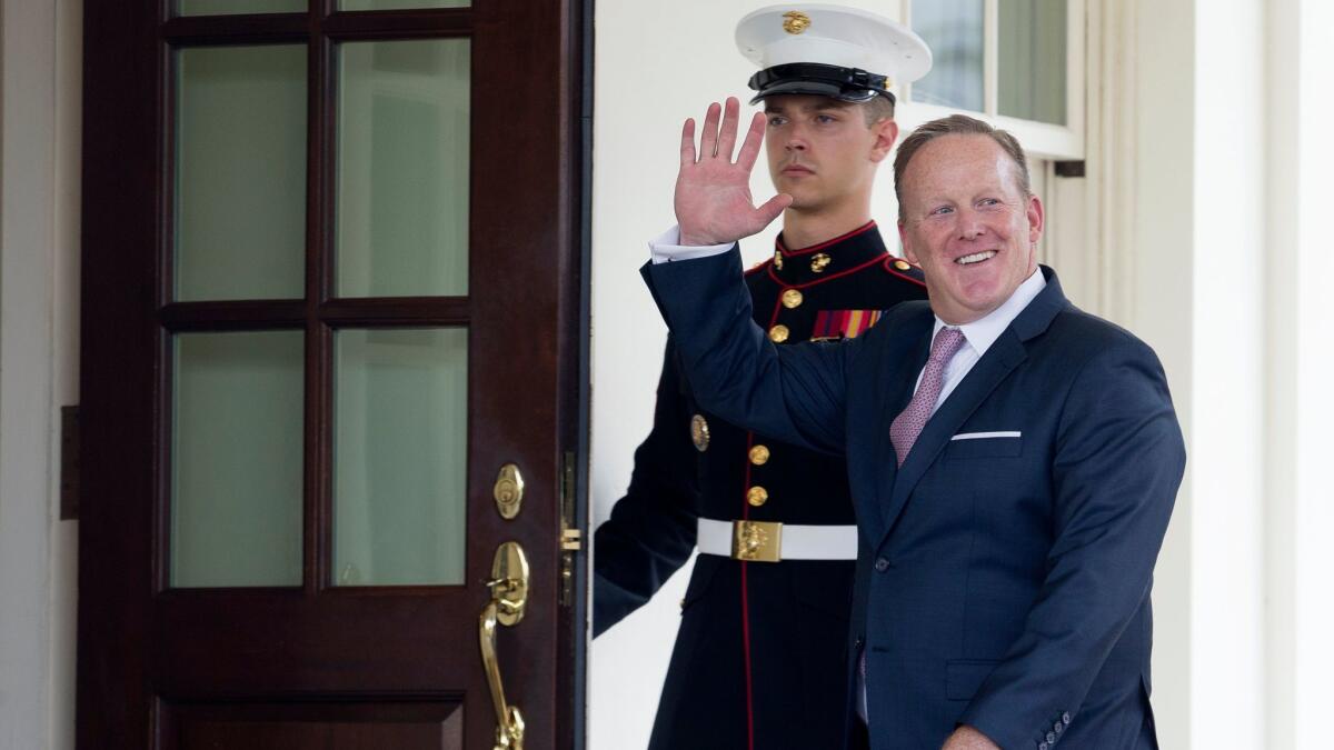 Outgoing White House Press Secretary Sean Spicer waves beside a US Marine as he enters the West Wing of the White House on July 21, 2017.