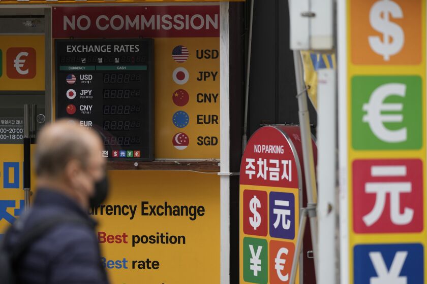 A man wearing a face mask walks past an electronic foreign currency exchange rates in downtown Seoul, South Korea, Wednesday, March 22, 2023. Asian shares advanced Wednesday after a Wall Street rally led by the banks most beaten down by the industry’s crisis.(AP Photo/Lee Jin-man)