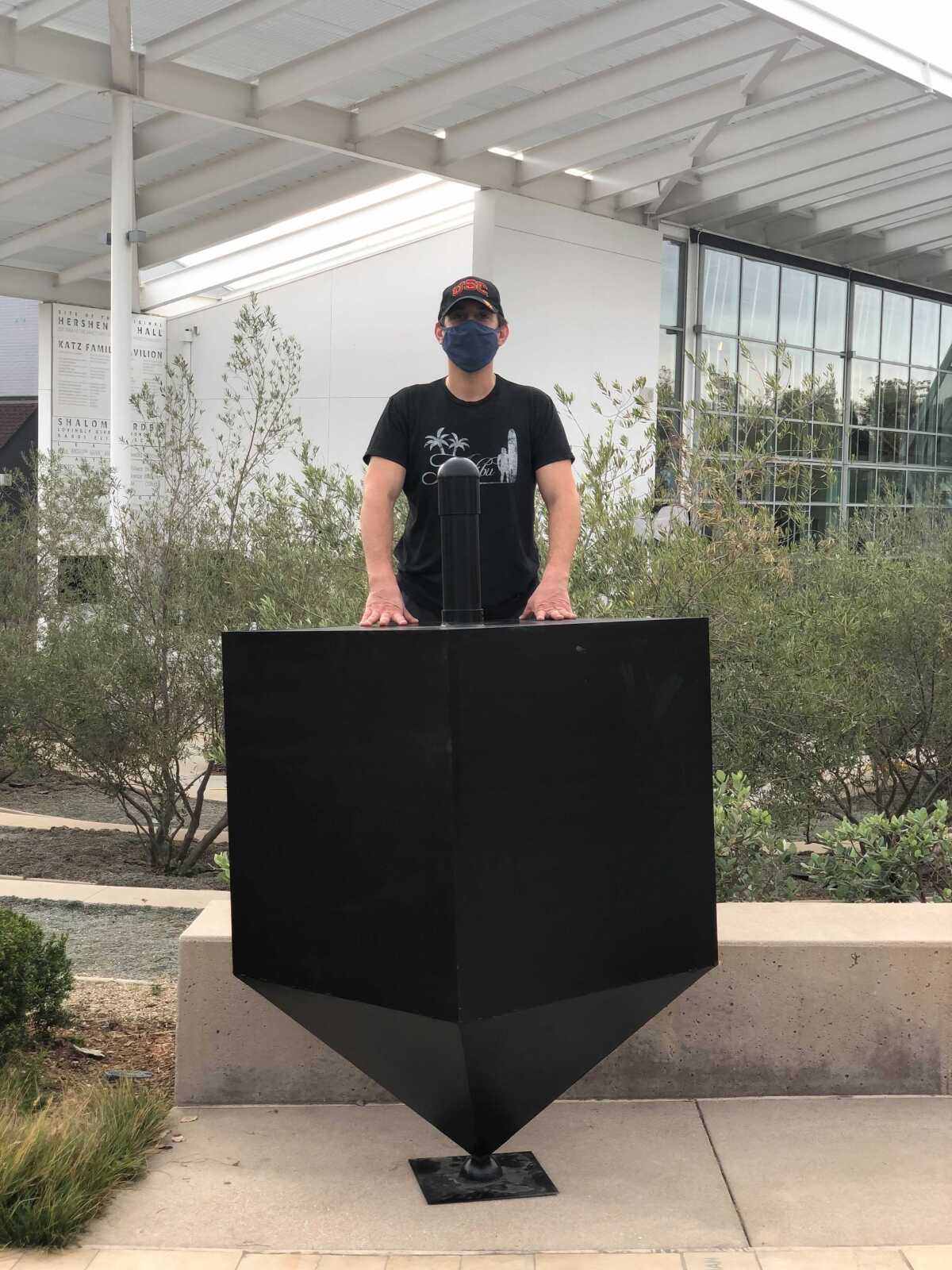 Michael Lam standing behind a giant dreidel