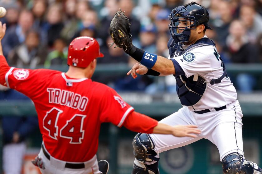 Former Mariners catch Jesus Montero takes a throw at the plate before tagging out the Angels' Mark Trumbo during a game in 2014.
