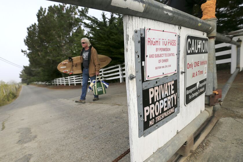 Mark Massara walks past a locked security gate at Martins Beach, where an access gate remains locked despite a judge's order to landowner Vinod Khosla to to open the gate and allow public access to the beach.