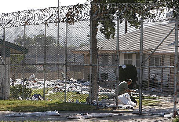 A state inspector goes over data in courtyard between two riot-damaged dorms.