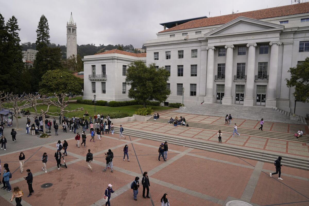 Students walk through a plaza in front of a building with columns