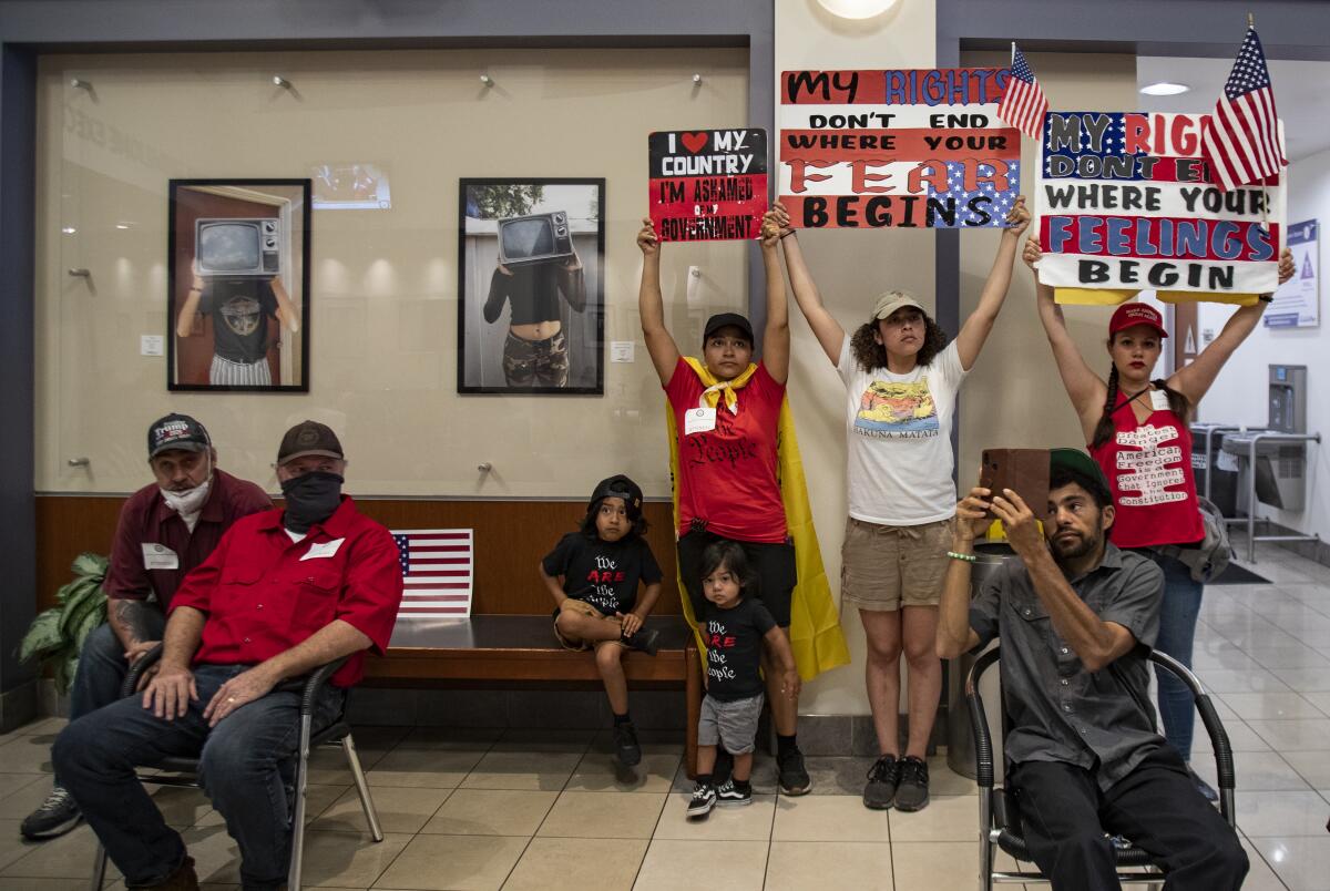 Protesters who want public health orders rescinded watch and listen to video monitors during the Riverside County Board of Supervisors meeting on May 5 in Riverside, Calif.