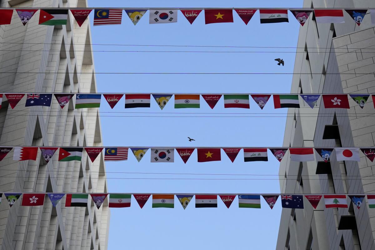 Las banderas de los países participantes se despliegan entre dos inmuebles, de cara a la Copa Asiática 