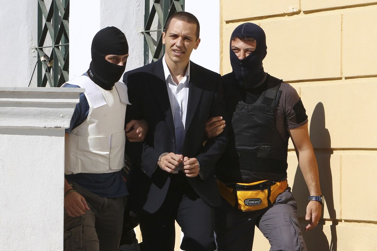 FILE - In this Tuesday, Oct. 1, 2013, file photo, lawmaker of the extreme far-right Golden Dawn party Ilias Kasidiaris, center, is escorted by anti-terror police to a court for a preliminary hearing into charges of participating in a criminal organization in Athens. Greece's government is seeking to ban a far-right political party led by the jailed former lawmaker from participating in a general election later this year, with a legislative initiative that has gained cross party support. Ilias Kasidiaris, 42, founded the Greek National Party two years ago. (AP Photo/Thanassis Stavrakis, File)