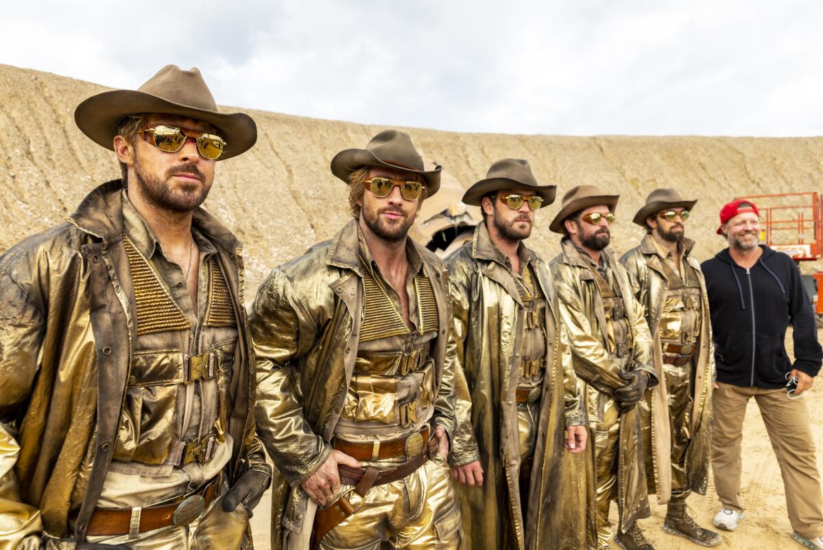 Five actors and stunt doubles in identical gold duster coats and hats pose on the set of "The Fall Guy."