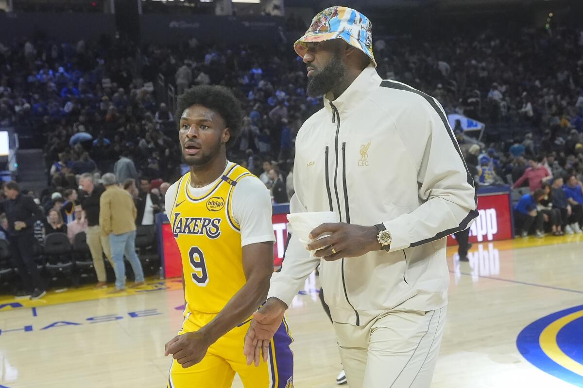 Lakers rookie guard Bronny James walks next to his father and Lakers star LeBron James before a preseason game.