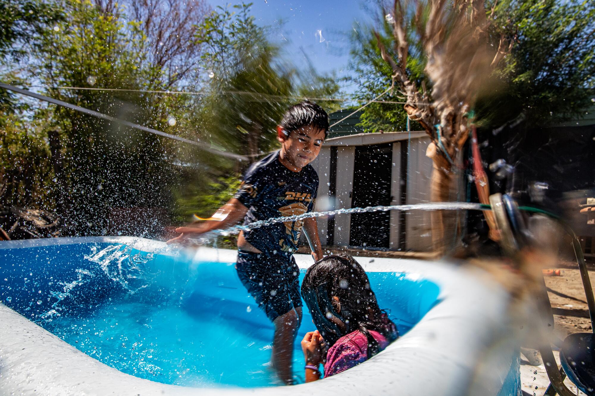 Two children play in a pool at their mobile home.