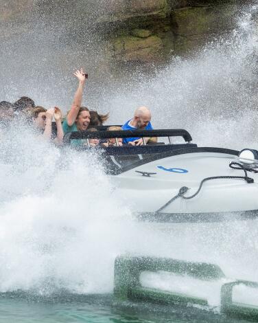 People are splashed with water on the 84-foot drop of Jurassic World: The Ride.