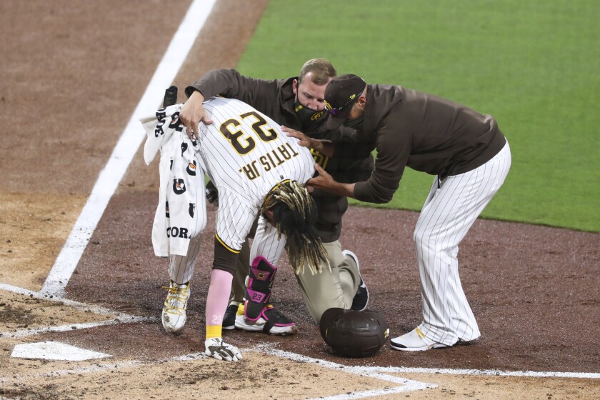San Diego Padres manger Jayce Tingler, right, and a trainer, center back, help Fernando Tatis Jr. (23) to his feet after Tatis hurt his shoulder while swinging at a pitch in the third inning of a baseball game against the San Francisco Giants, Monday, April 5, 2021, in San Diego. (AP Photo/Derrick Tuskan)