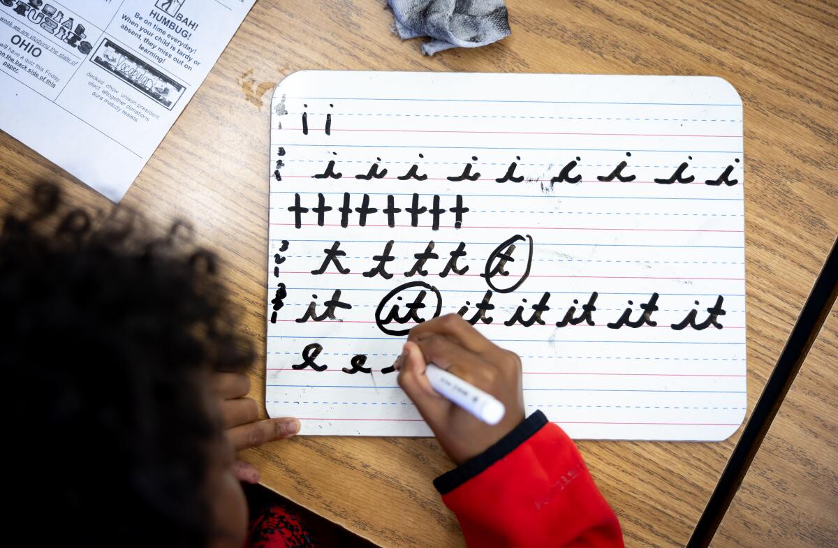 An over the shoulder image shows a young person writing the letter 't' in cursive.